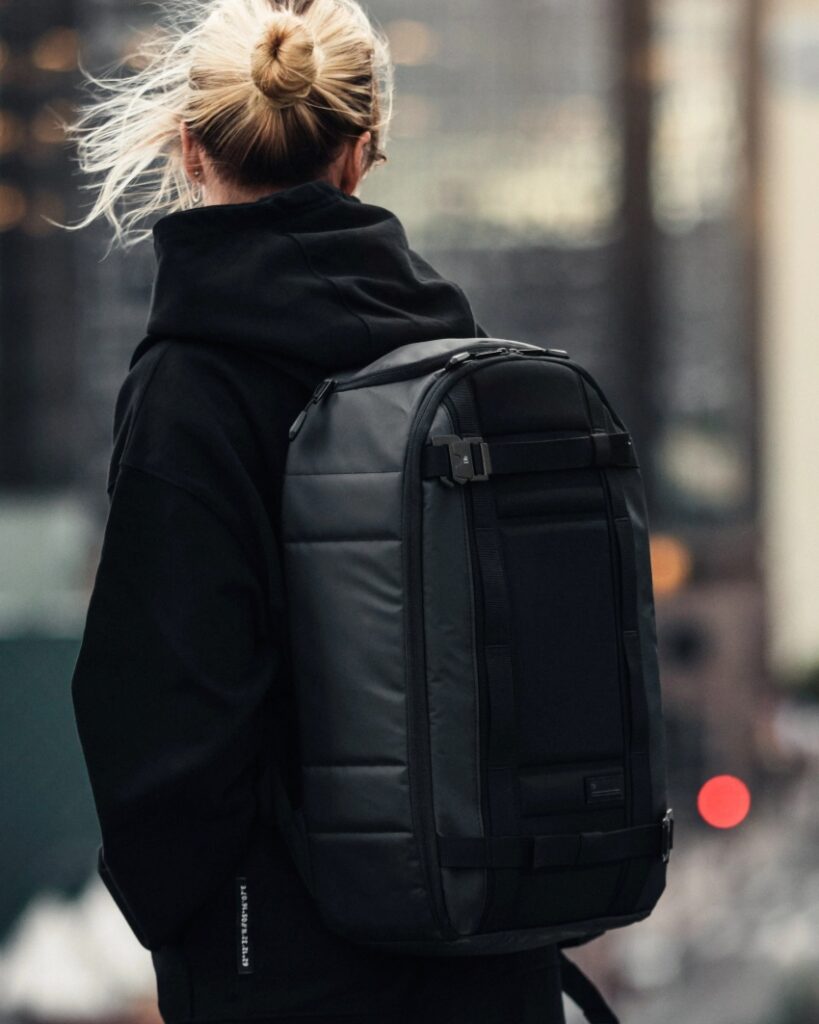 woman carrying black travel backpack